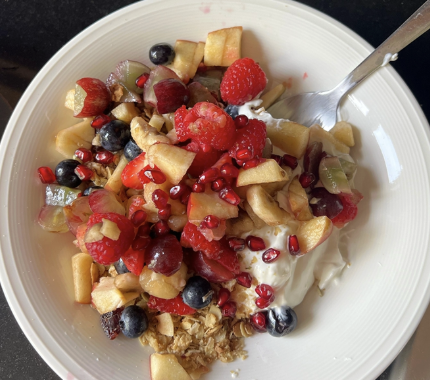 Yoghurt bowl loaded with granola, raspberries, blueberries, pomegranate and apple
