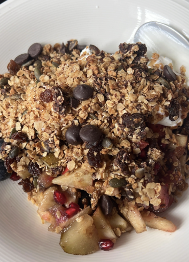 Big bowl of granola with chocolate chips, pumpkin seeds and stewed apple