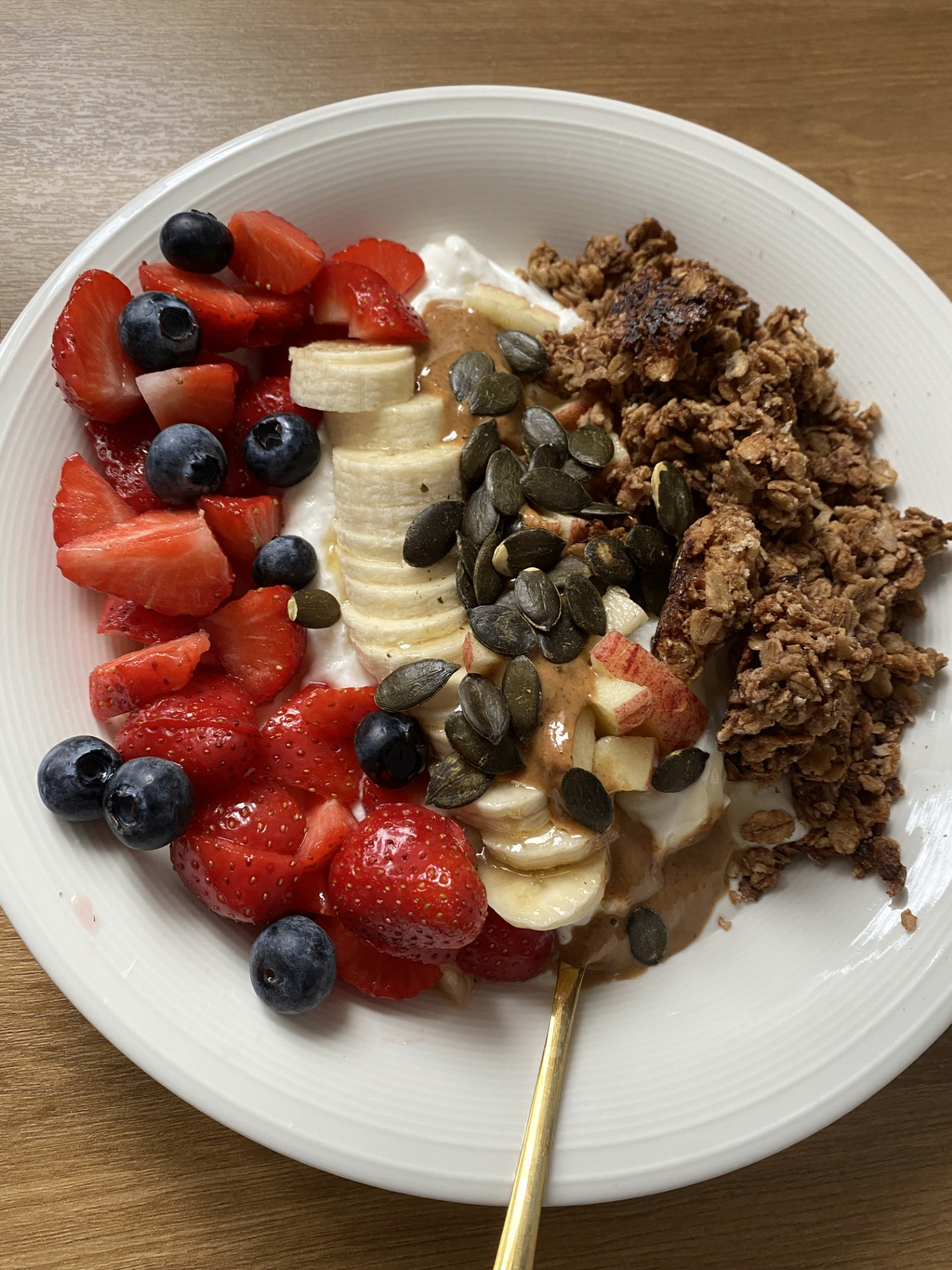 Granola bowl with strawberries, blueberries, banana, pumpkin seeds and peanut butter