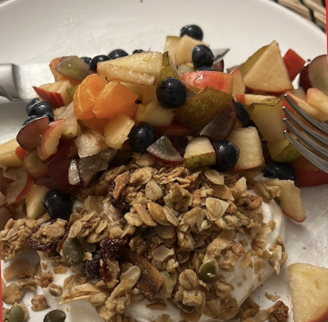 Granola with pumpkin seeds and raisins over yoghurt and chopped fruit